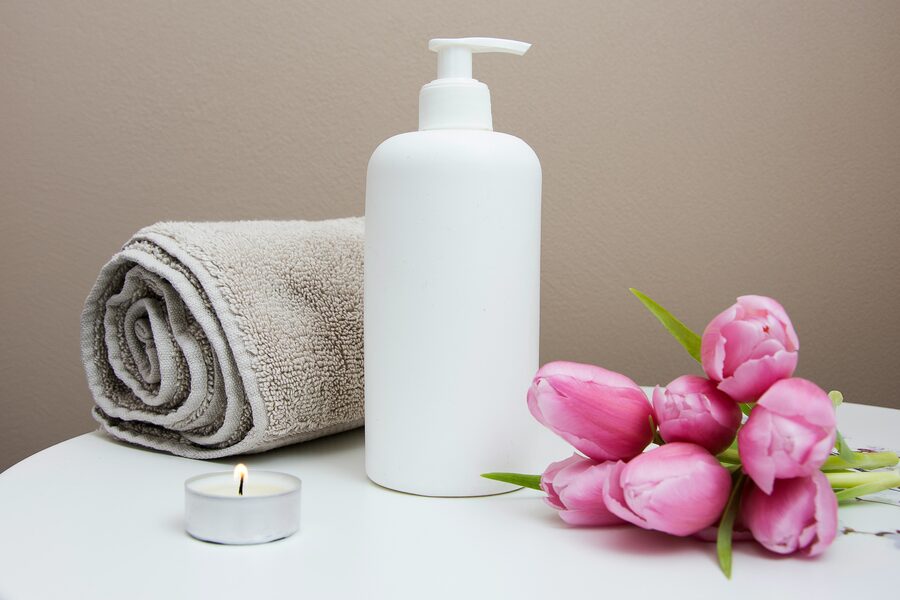 Handduk, lotion, blommor och ljus inför massagebehandling